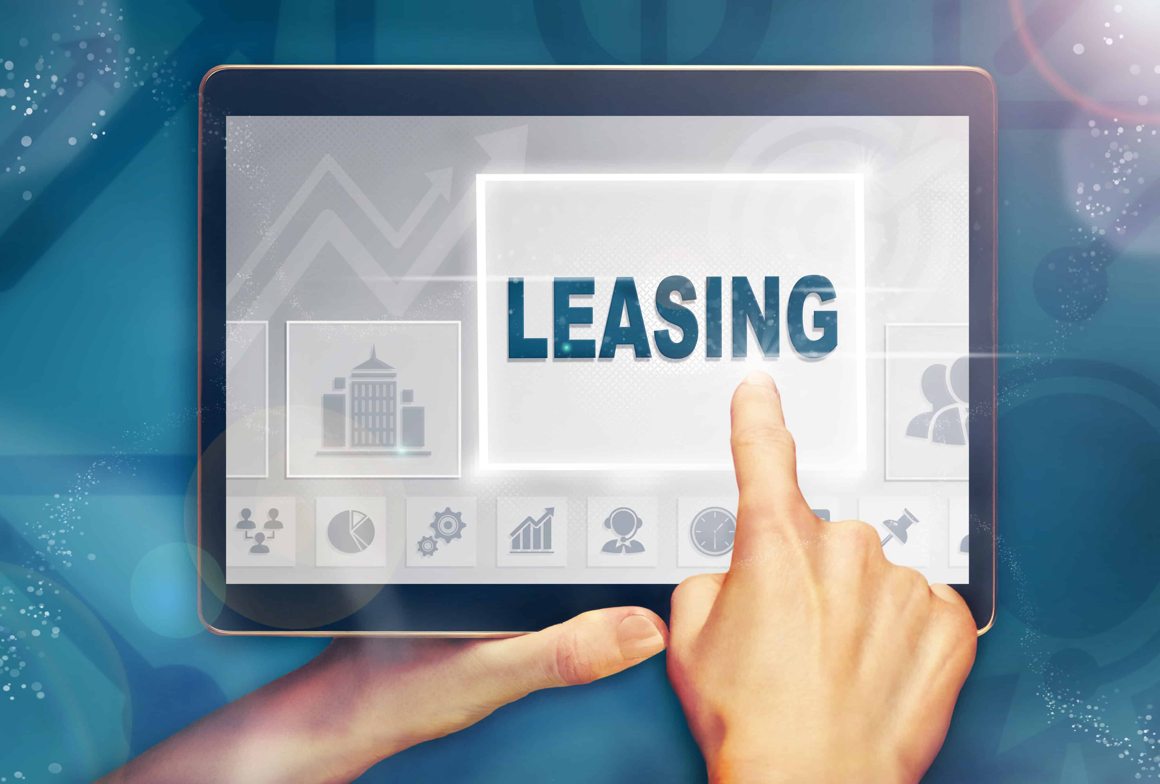 A hand holiding a computer tablet and pressing a Leasing business concept.