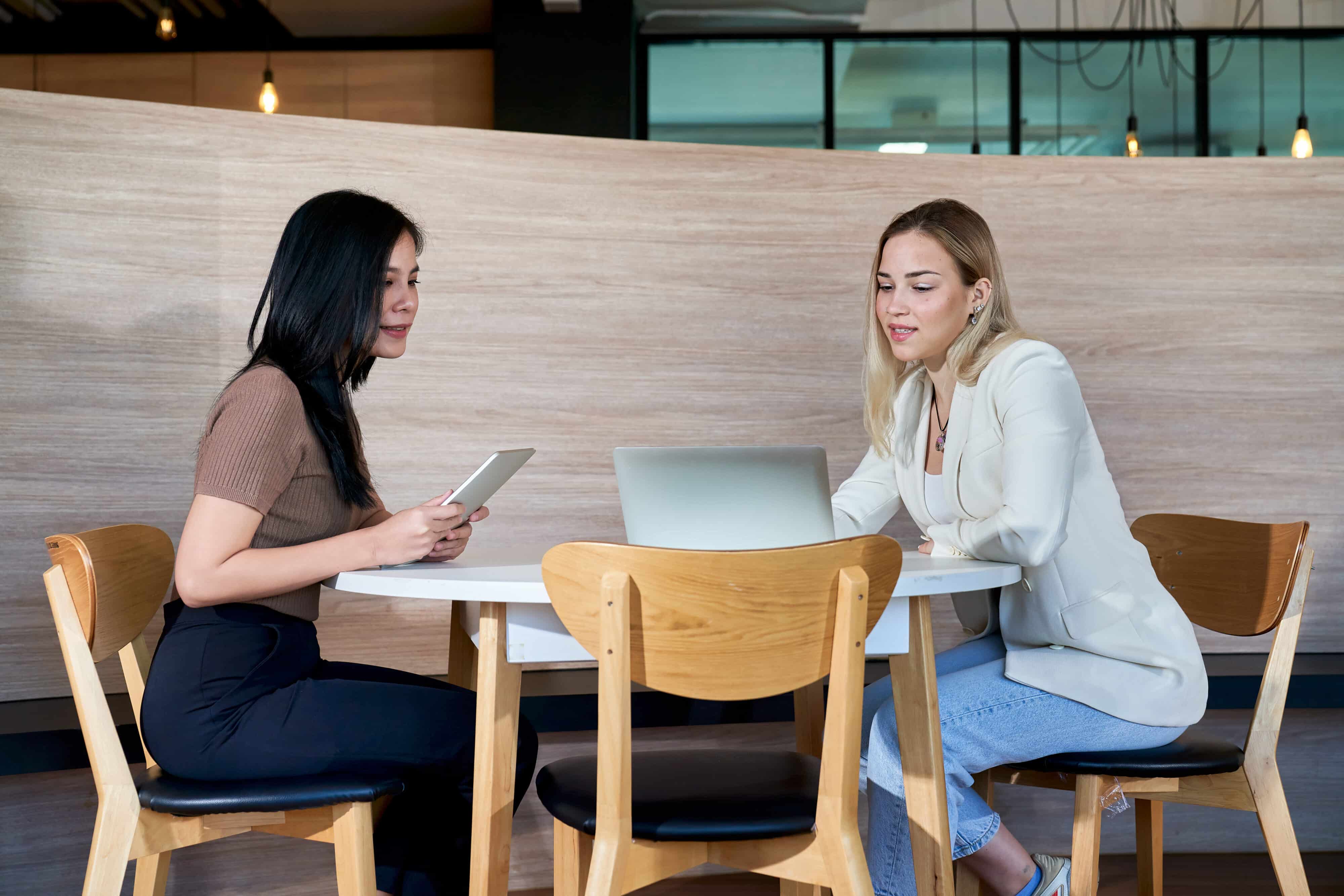 Two female are working with laptop in co working space.
